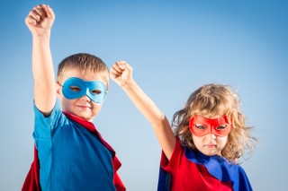 Superhero children against summer sky background. Kids having fun outdoors. Boy and girl playing. Success and winner concept